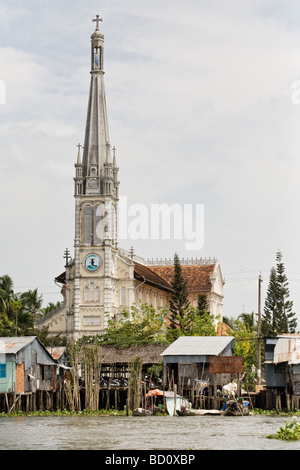 A church behind a floating village in the Mekong Delta, Vietnam Stock Photo