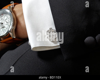 bling bling closeup of a dollar sign silver with diamonds cufflink tuxedo smoking suit breitling watch Stock Photo
