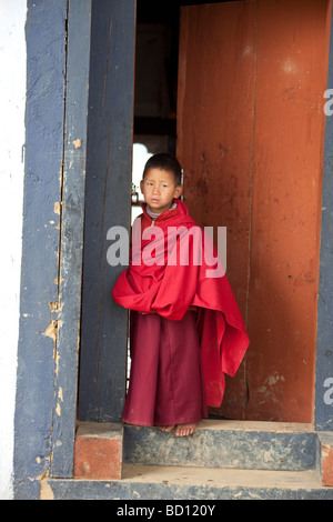 Young monk in red Gangteng Gonpa Monastery nr village of Gantey, Phobjika valley, Wangdue Phodrang District, central Bhutan. Stock Photo