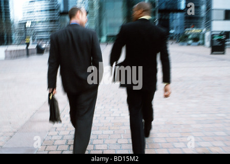 Businessmen walking together along city sidewalk Stock Photo