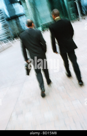 Businessmen walking together along city sidewalk Stock Photo