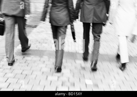 Business professionals walking together along sidewalk, rear view, waist down Stock Photo