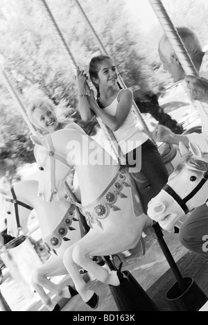 Girl riding carousel with her grandparents