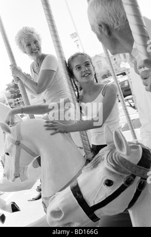 Girl riding carousel with her grandparents