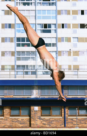 Man diving, high rise building in background Stock Photo