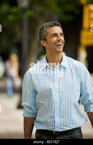 Man walking outdoors, smiling, looking away Stock Photo
