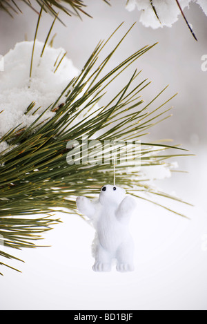Polar bear ornament hanging from snow-covered branch Stock Photo