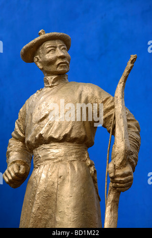 An archer in traditional Mongolian dress shoots an arrow from a bow ...