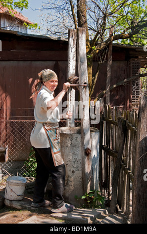 Romanian farm woman drawing water from well in countryside near Targoviste in Wallachia Stock Photo