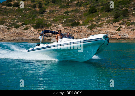 Men in fast white inflatable boat near the coastline Stock Photo