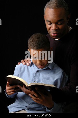 African American father and son reading Bible over a black background Stock Photo
