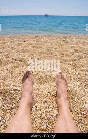 Legs and feet on shingle beach at Skala on the Greek island of Kefalonia Greece GR Stock Photo