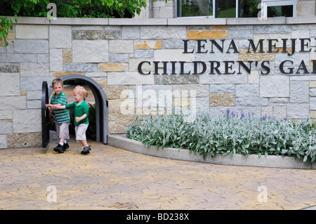 Children walk through the miniature gate at the Lena Meijer Childrens Garden part of the Frederik Meijer Gardens Sculpture Park Stock Photo