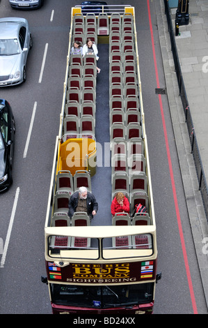 Aerial birds eye view looking town from above at top deck of London double decker hop on hop off nearly empty sightseeing tour bus England UK Stock Photo