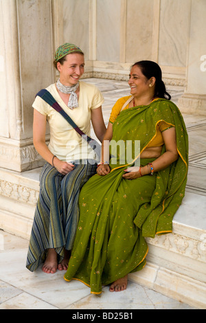 Western woman tourist sitting with an Indian woman tourist at the Nagina Masjid (ladies' mosque). Agra Red Fort, Agra. India. Stock Photo