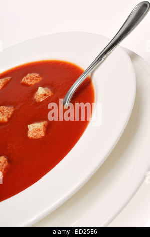 Bowl of tomato soup and  croutons with spoon on white background. Stock Photo