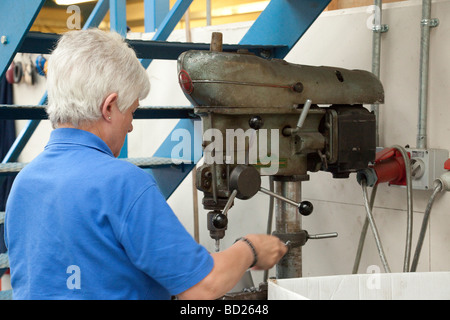woman using a drilling machine / pillar drill / drill press in a UK factory Stock Photo