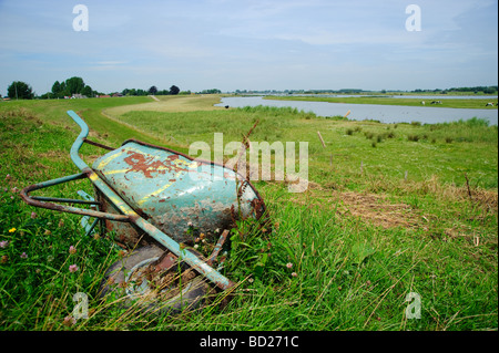 Old rusty wheelbarrow lying in a green meadow Stock Photo