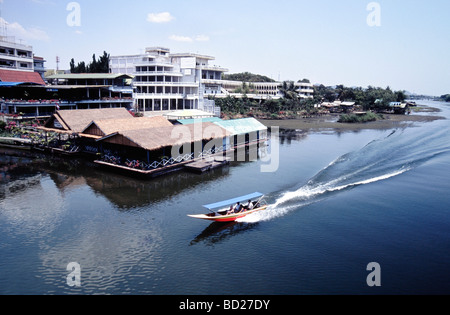 A boat passing by floating restaurants and War Museum near Bridge Over River Kwai at Kancanaburi Province in Thailand Stock Photo