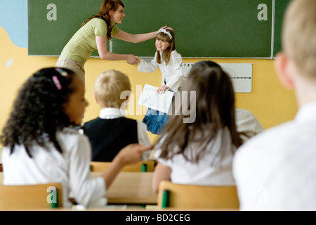 Teacher giving school reports to children Stock Photo