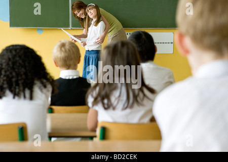 Teacher giving school reports to children Stock Photo