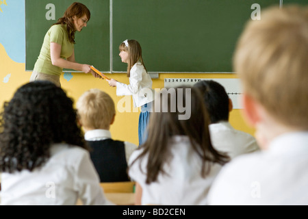 Teacher giving school reports to children Stock Photo