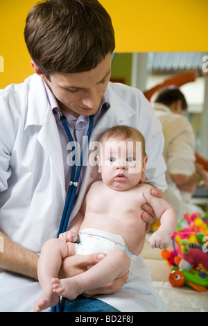 Pediatrician doctor examines baby with stethoscope checking heart beat ...