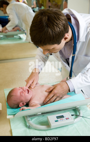 doctor putting infant on weighing scale Stock Photo