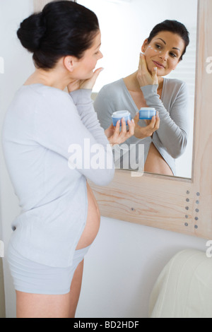 Pregnant woman applying face cream