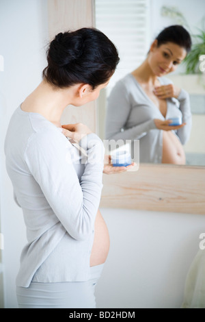 Pregnant woman applying cream to chest