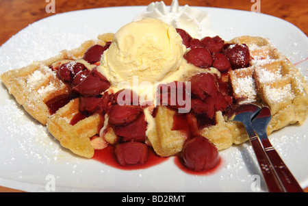 Fresh waffles with red cherries ice cream and whipped cream Focus on centre of image Stock Photo