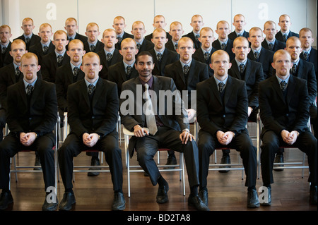 1 black businessman with 25 white clones Stock Photo