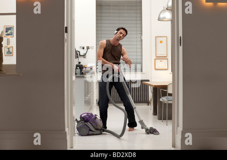 man vacuuming and listening to music Stock Photo
