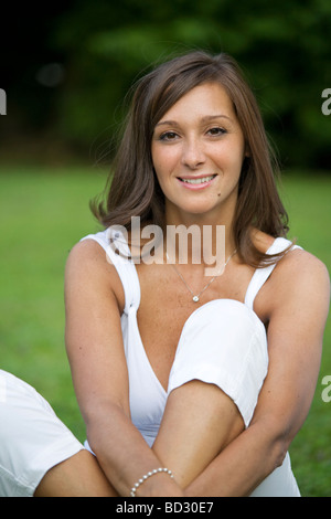 Beautiful woman looking at camera and seated on the grass Stock Photo