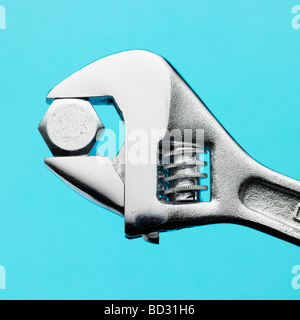 Adjustable spanner and nut on blue background. Stock Photo
