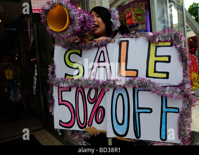 Young Japanese woman announce sales at a shop in downtown Tokyo Japan Stock Photo