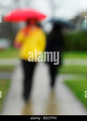 People with umbrellas on a sidewalk in the rain Stock Photo