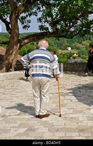 Elderly retired old man standing resting relaxing with walking stick on bright sunny day in France Stock Photo