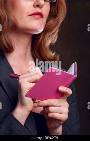Close up of woman writing in pink notebook Stock Photo