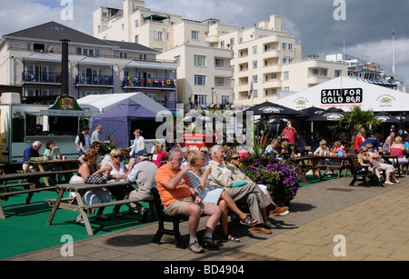 Cowes regatta week visitors relaxing on The Parade a waterfront area of catering bars and food outlet tents Isle of Wight UK Stock Photo