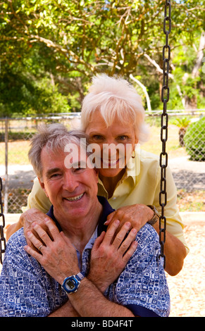 Retired senior couple having fun together at playground on swing Stock Photo