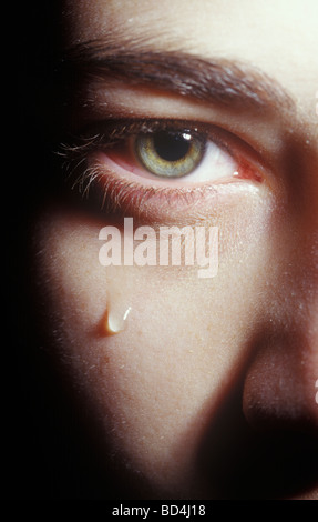 close up of an eye with a tear dripping down the cheek of a young woman Stock Photo