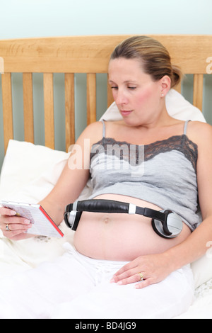 pregnant woman playing music for unborn baby with headphones on stomach  Stock Photo - Alamy