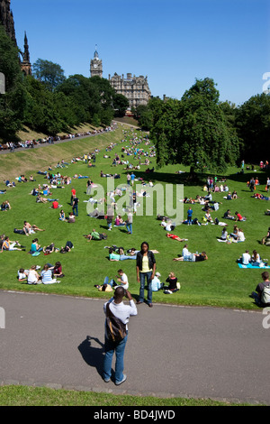 Sunbathers in East Princess Street Gardens in Edinburgh Scotland with Balmoral Hotel in distance Stock Photo