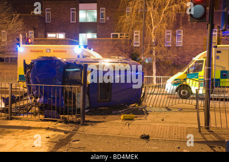 Night time car crash scene showing ambulances in attendance and lit by blue neon lights from surrounding emergency vehicles Stock Photo