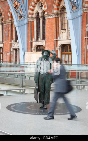 A passenger passes in front of the Sir John Betjeman statue in the new St Pancras International Station, London, UK. Stock Photo