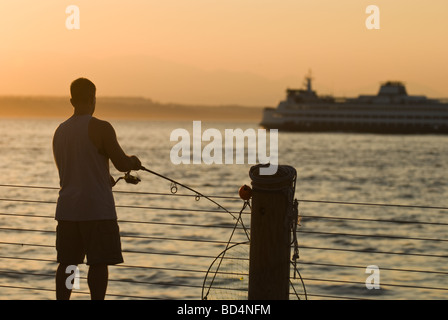 A man fishes off the pier at Alki Beach Park in Seattle. Stock Photo