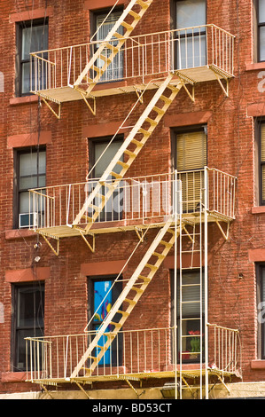 House with metal fire escape stairs ladders on a red brick building in Manhattan, New York City, USA. Urban architectural detail. Stock Photo