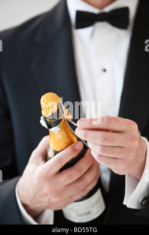 Champagne bottle being opened by a man in a tuxedo Stock Photo