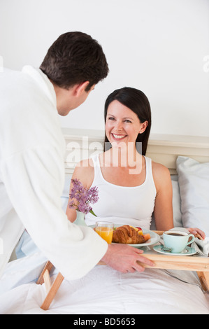 A man bringing a woman breakfast in bed Stock Photo